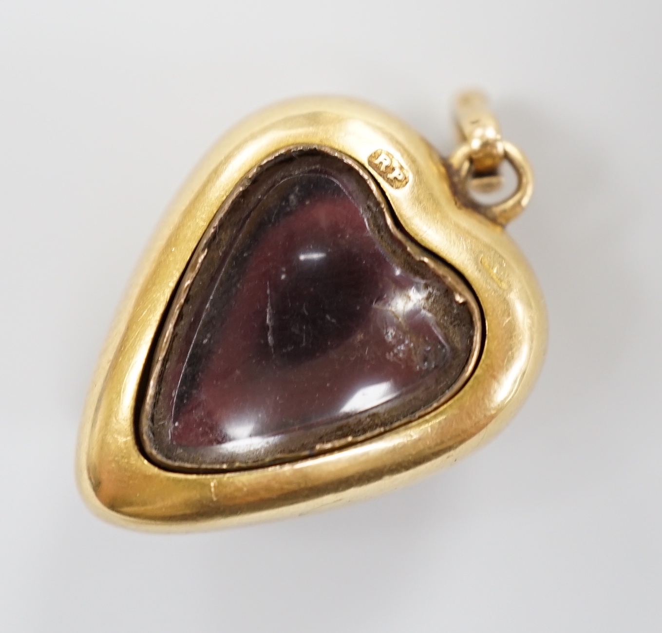 A late Victorian yellow metal (stamped 18) and cabochon garnet set heart shaped pendant, with glazed back, 22mm, gross weight 5.7 grams.